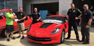 Local Police with Greenwood Chevrolet Chevy All Stars standing next to a Red Corvette